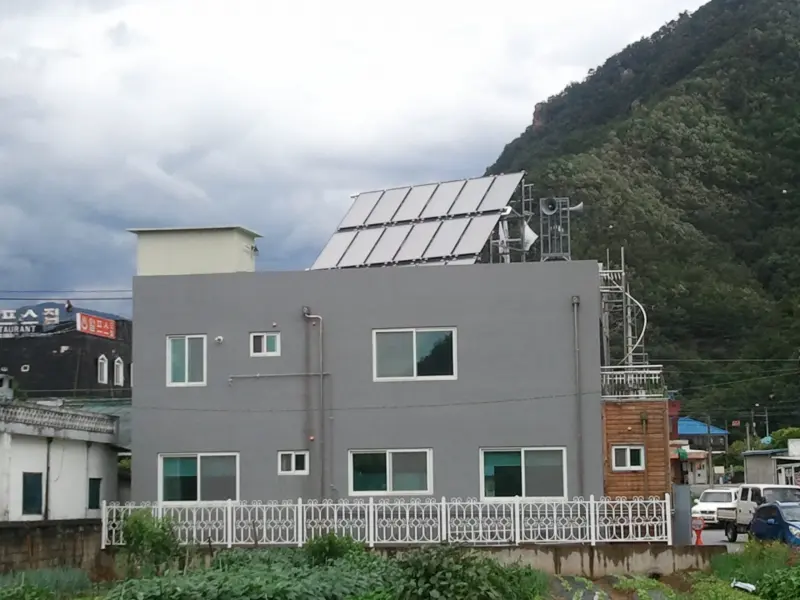 산을 배경으로 한 건물 옥상의 태양열 집열기