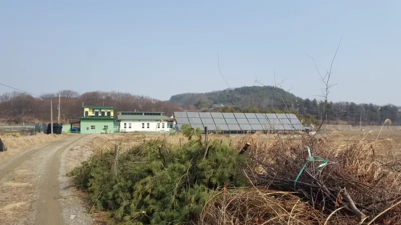태양열 집열설비 참고 사진(공기식 온풍기 확인 안 됨) · 들판 옆 부지에 설치된 평판형 태양열 집열기